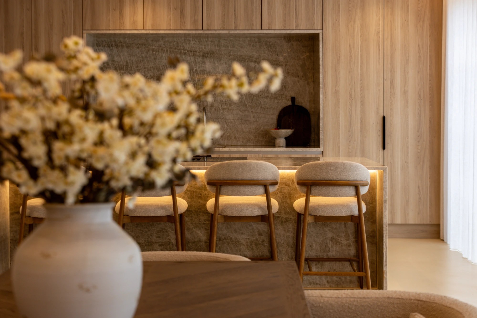 Warm neutral kitchen with a stone island and splashback